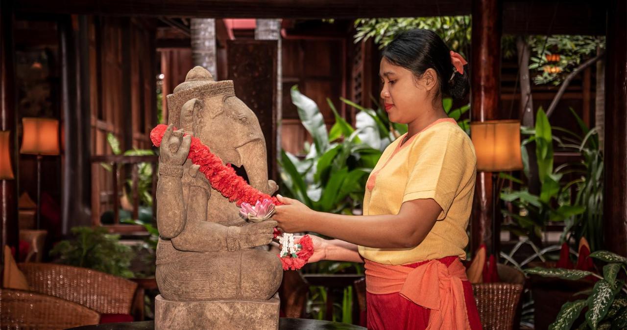 Angkor Village Hotel Siem Reap Eksteriør bilde A woman in Thailand, wearing traditional Thai clothing, garlands a statue of the Hindu god Ganesha.